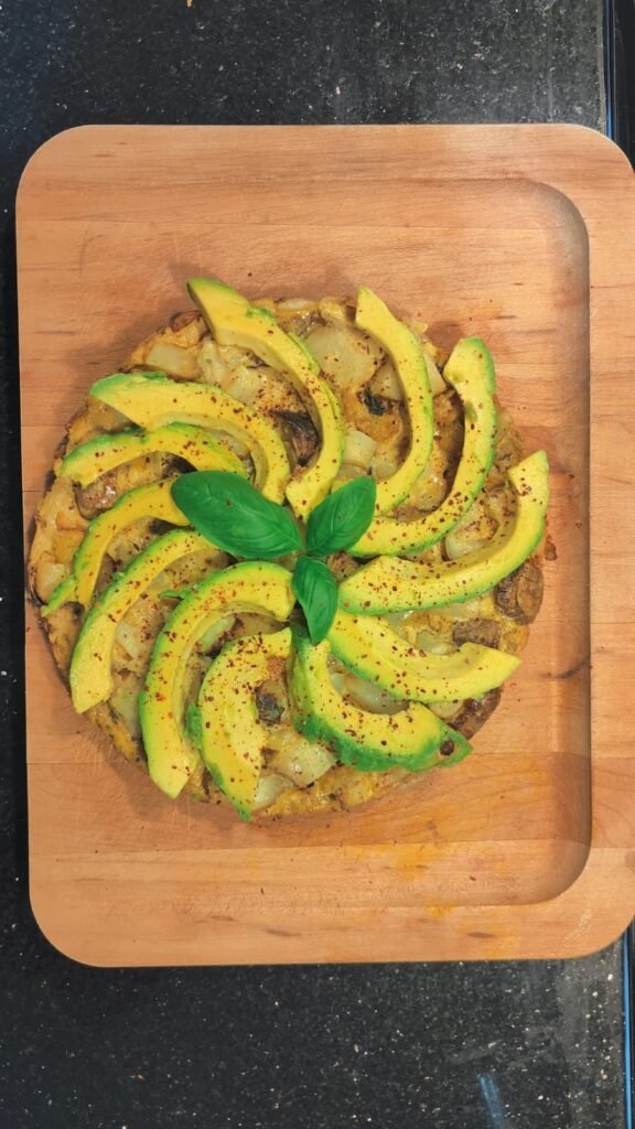Sliced avocado fanned over toasted sourdough with basil on a wooden board