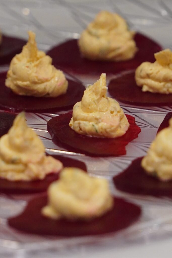Beetroot canapés piped with whipped cheese on a silver platter
