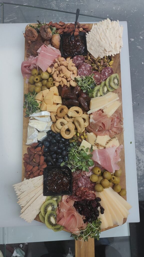 Long grazing board with cured meats, cheeses, olives, nuts and fresh fruit