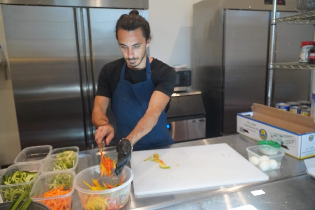 Chef Bruno Di Benedetto slicing vegetables at a stainless steel prep bench
