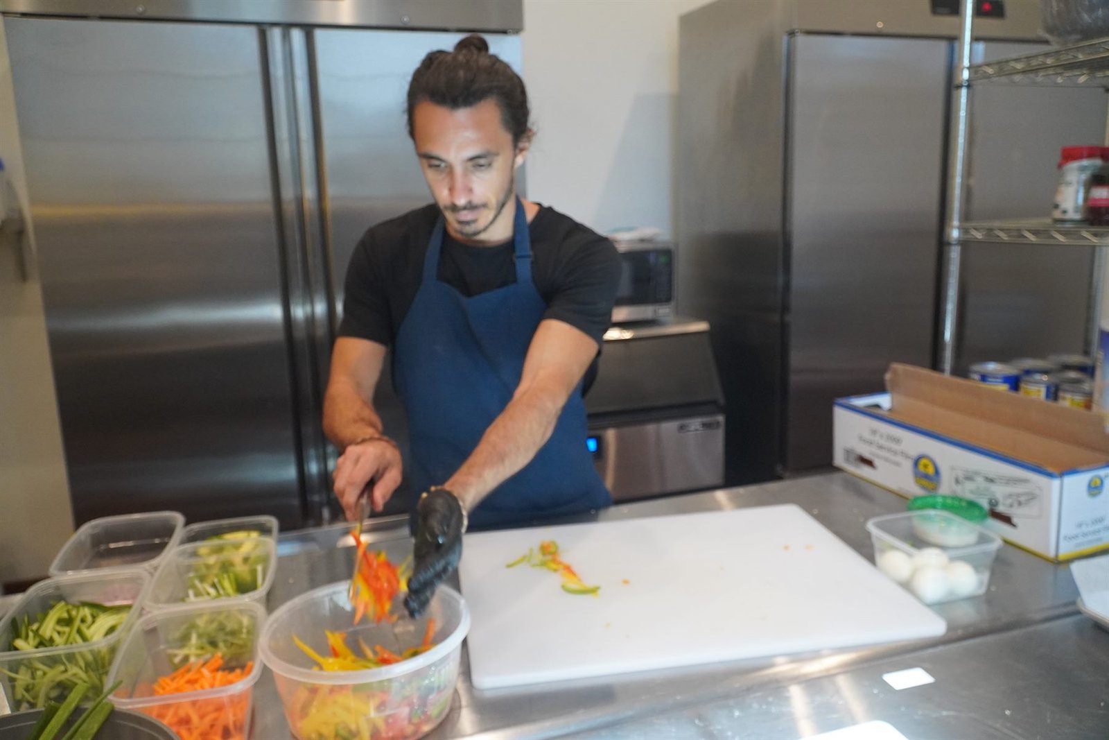 Chef Bruno Di Benedetto slicing vegetables at a stainless steel prep bench