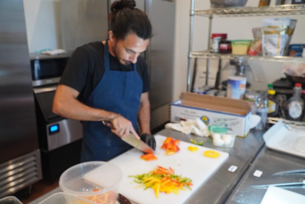 Chef preparing vegetables at a kitchen prep station