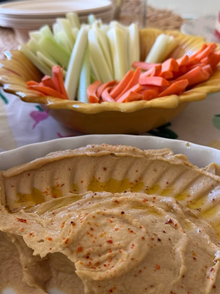 Platter of cut raw vegetables served with a bowl of whipped hummus