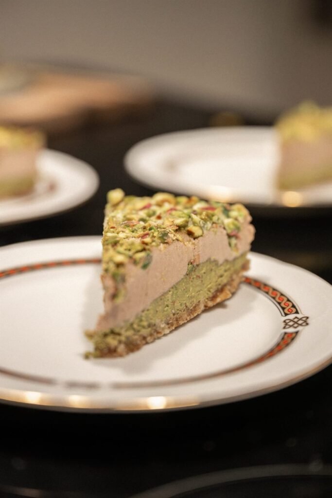 Slice of pistachio cream cake on a gold-rimmed dessert plate