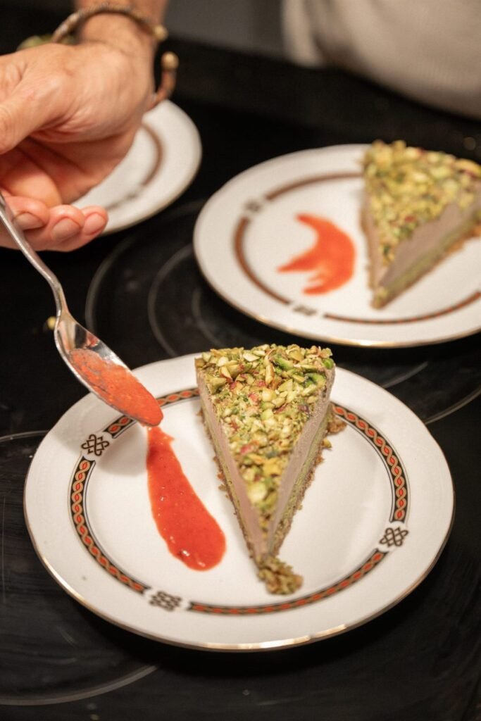 Slice of pistachio cake plated with fruit coulis