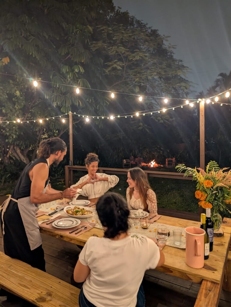 Guests gathered around a long table under string lights at a private dinner party in Miami