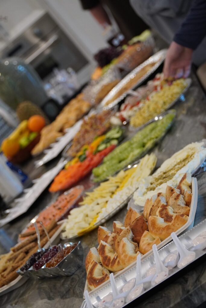 Large catering spread with platters of fruit, pastries and mezze laid across a marble counter