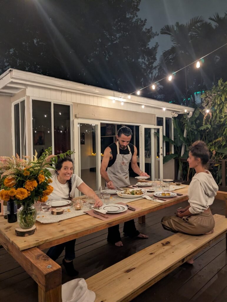Guests seated at a long wooden table under string lights at a private chef dinner in Miami