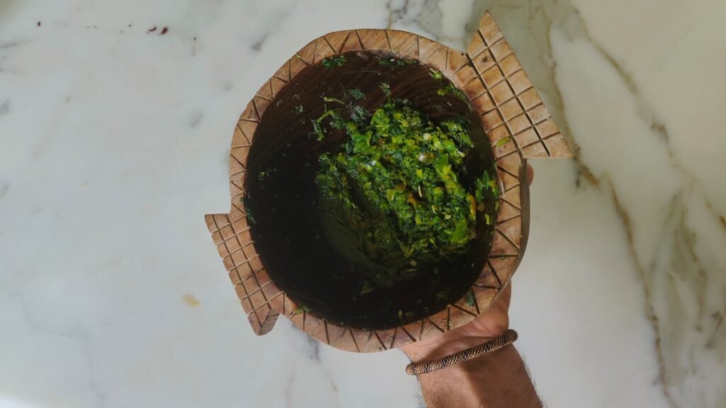 Hands holding a bowl of freshly made herb pesto over a marble counter
