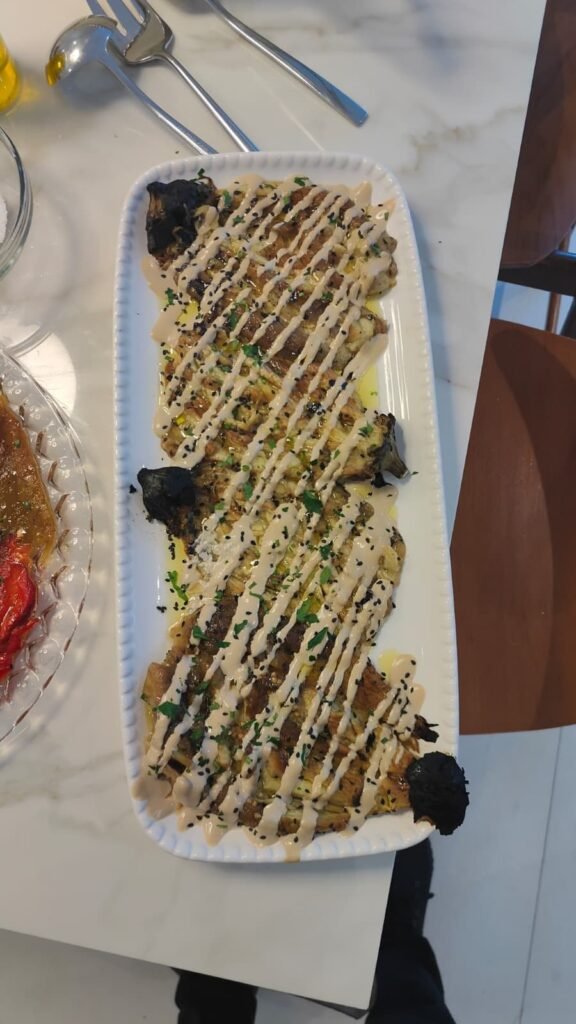 Long white platter of herb-crusted fish with green drizzle