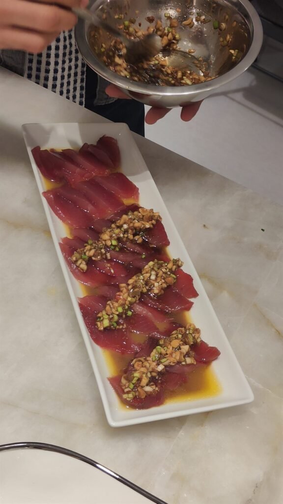 Sliced sesame-crusted tuna tataki arranged on a white rectangular platter