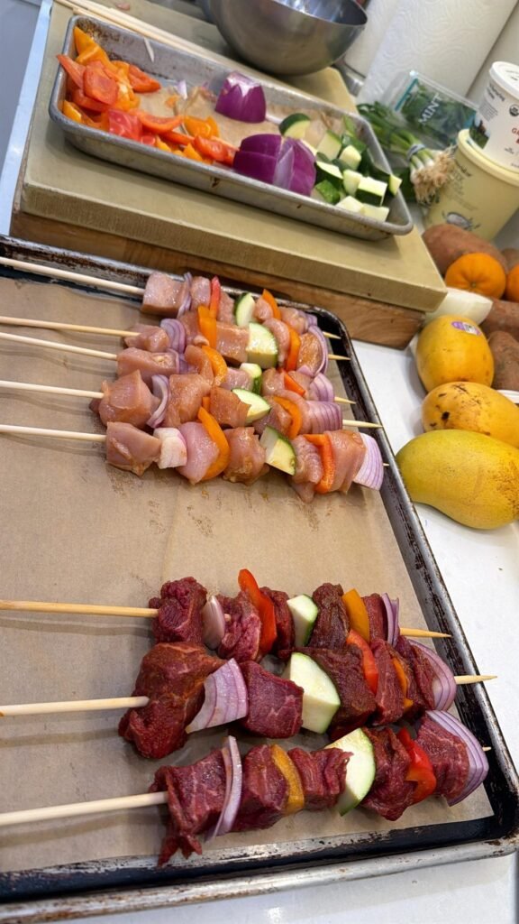 Vegetable and protein skewers laid out on a tray before grilling